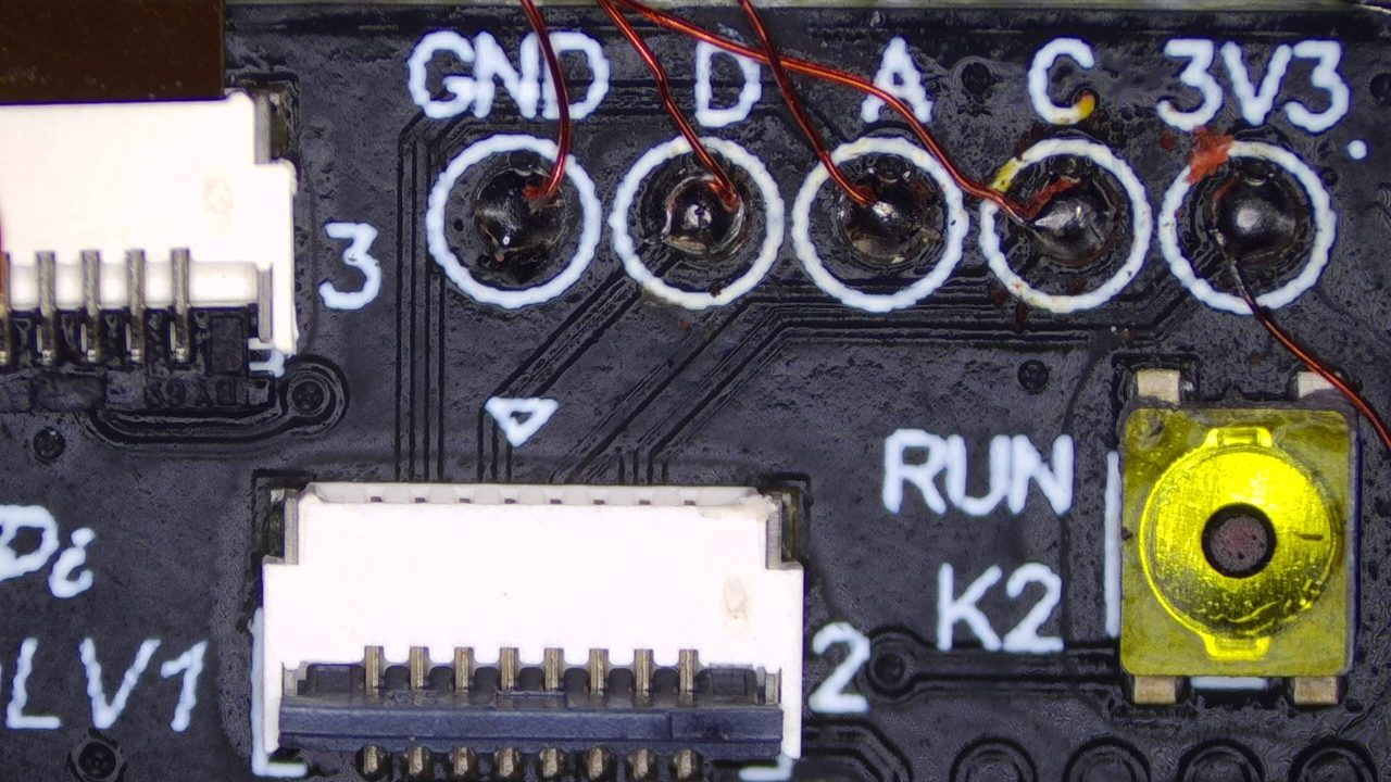 Vue macro d'une puce PICOFLY RP2040 : fils émaillés soudés un à un sur les pastilles GND, D, A, C et 3V3.